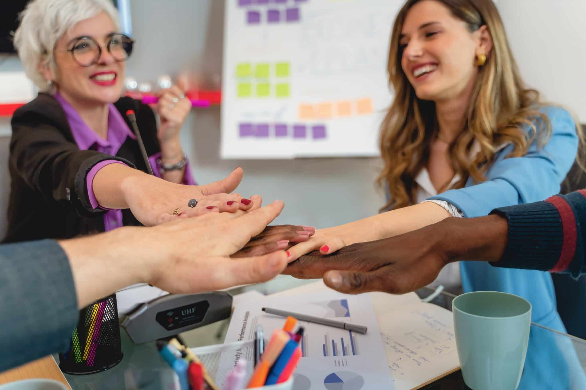 Diverse business team joining hands during strategy meeting