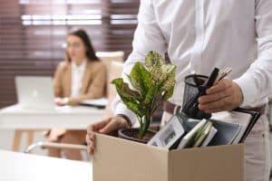 cropped image of laid off employee holding personal items in box