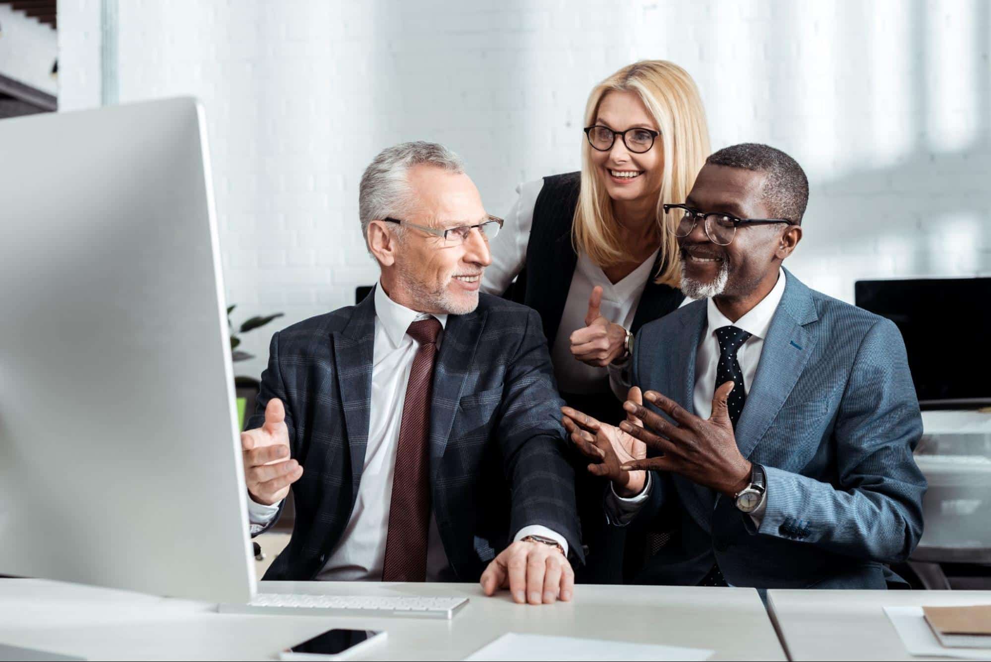 coworkers gathered around computer monitor